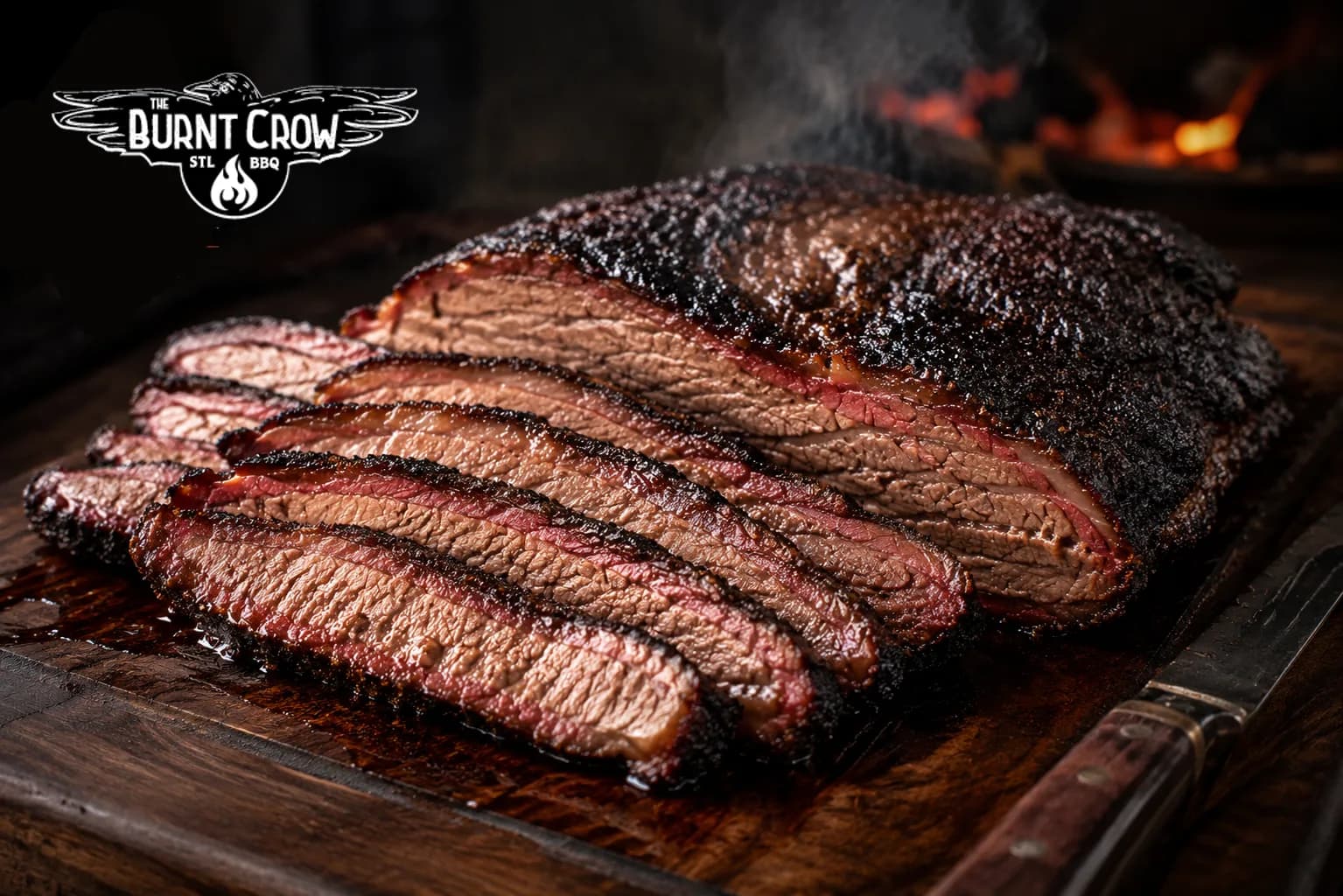 A smoked beef brisket on a wooden board, sliced to show its dark peppery bark and pink smoke ring, with the fire still burning behind it.